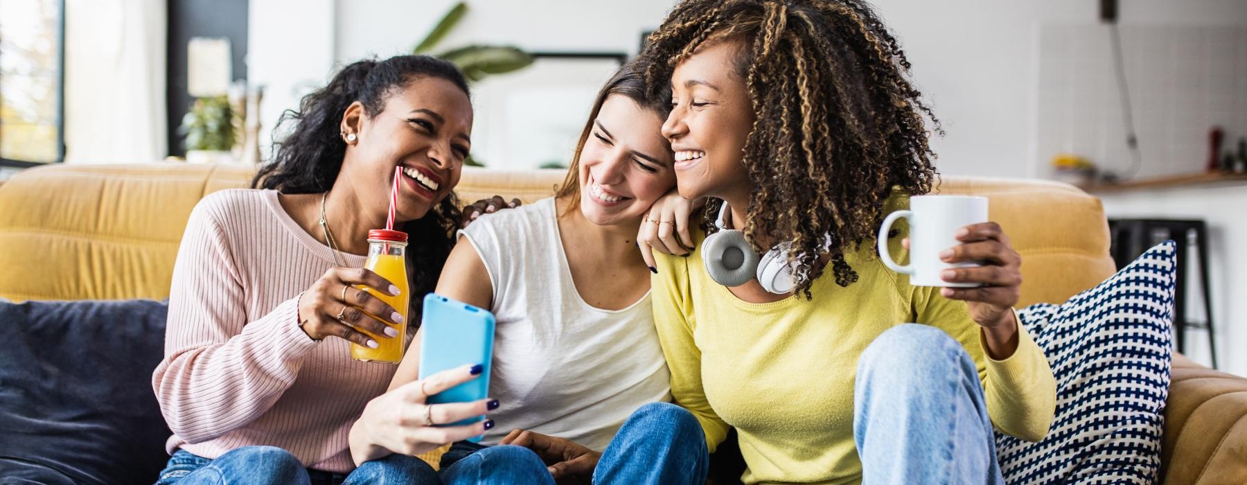 a group of women sitting on a couch looking at a phone